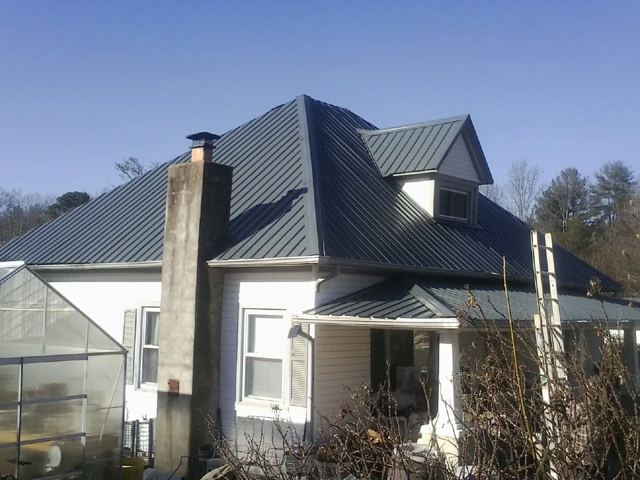 Dark blue standing seam metal roof on a white farmhouse with dormer — Slate & Tile Roof Repair by Roofing Brothers in Hopwood