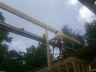 Carpenter setting a ridge beam over a new addition frame — Ice Dam Removal by Roofing Brothers in Hopwood