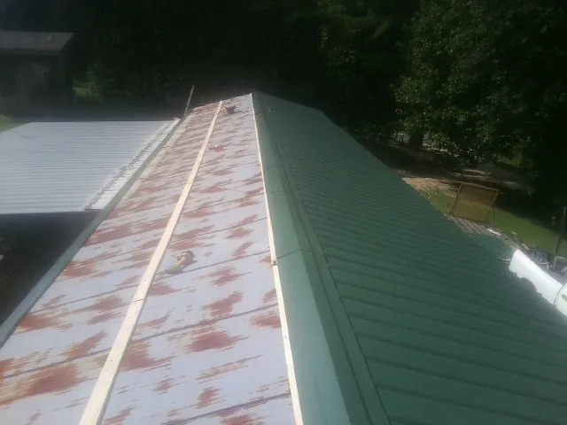 Old rusted panels beside newly installed green metal roofing — Wind Damage Roof Repair by Roofing Brothers in Hopwood