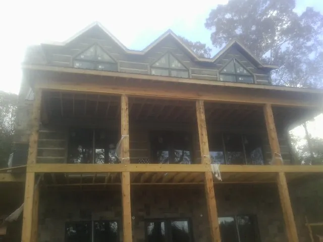Dormers and porch framing on a large log home under construction — Roof Coating work by our crew in Hopwood