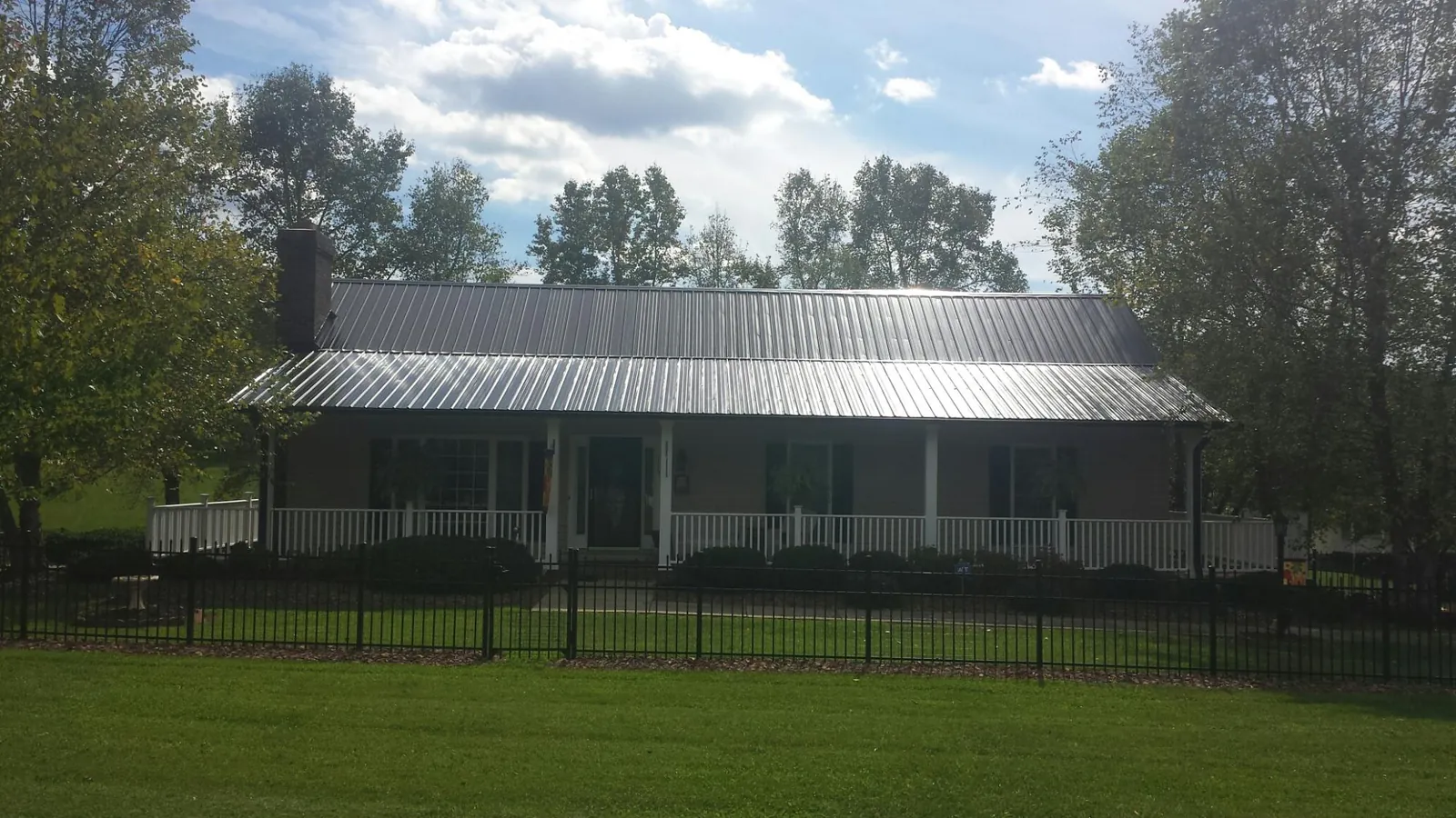 Gray metal roof on a brick ranch with a full width front porch — Gutter Guard Installation work by our crew in Hopwood