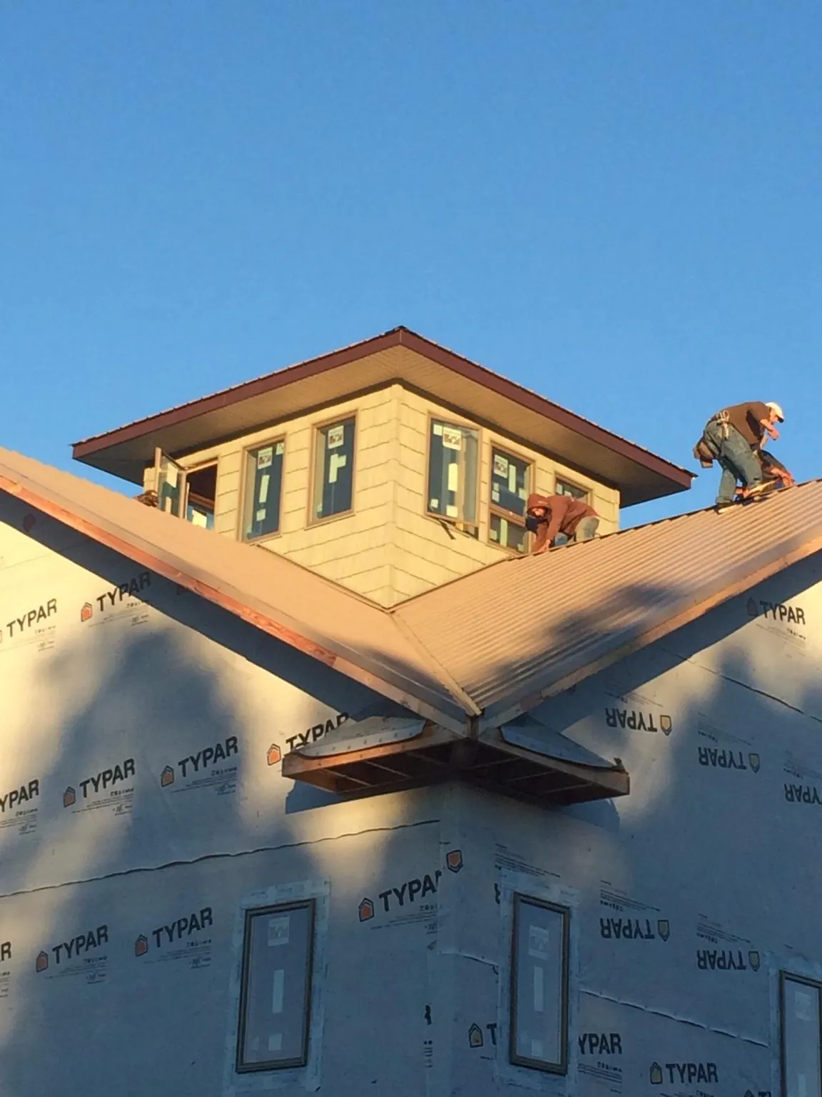 Roofers working around a rooftop cupola on a new metal roof at sunset — Roof Waterproofing in Hopwood by Roofing Brothers